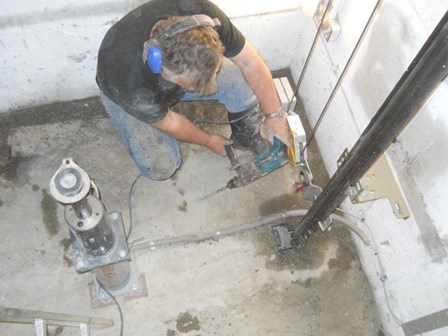 Lift pit waterproofing was required to prevent water leaking into the lift pit.  The technician is drilling to allow for crack injection of a resin sealant, at Bangor, Co. Down, Northern Ireland